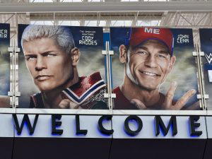 Several graphics of WWE Superstars hang above on a bridge at the airport. This photo shows Cody Rhodes and John Cena.